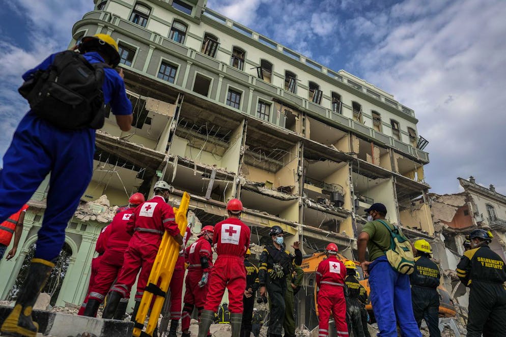 Red Cross and rescue teams wait to enter the site of a deadly explosion that destroyed the five-star Hotel Saratoga, in Havana, Cuba, Friday, May 6, 2022. A powerful explosion apparently caused by a natural gas leak killed at least 18 people, including a pregnant woman and a child, and injured dozens Friday when it blew away outer walls from the luxury hotel in the heart of CubaâÄ™s capital. (AP Photo/Ramon Espinosa)