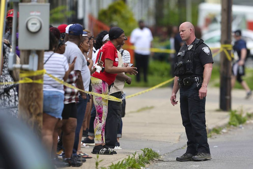 Police speak to bystanders while investigating after a shooting at a supermarket on Saturday, May 14, 2022, in Buffalo, N.Y. Officials said the gunman entered the supermarket with a rifle and opened fire. Investigators believe the man may have been livestreaming the shooting and were looking into whether he had posted a manifesto online. (AP Photo/Joshua Bessex)