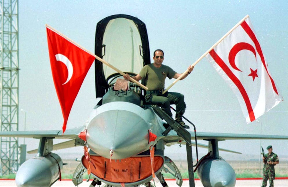 CYP02 - 19980619 - GECITKALE, CYPRUS : A pilot waves the Turkish and the Turkish-Cypriot flag as he sits on an F-16 Turkish warplane at the airbase in Gecitkale 19 June. The final three Turkish warplanes sent to Cyprus on Thursday in retaliation for a similar Greek move left the Mediterranean island for Turkey on Friday. EPA PHOTO/HURRIYET