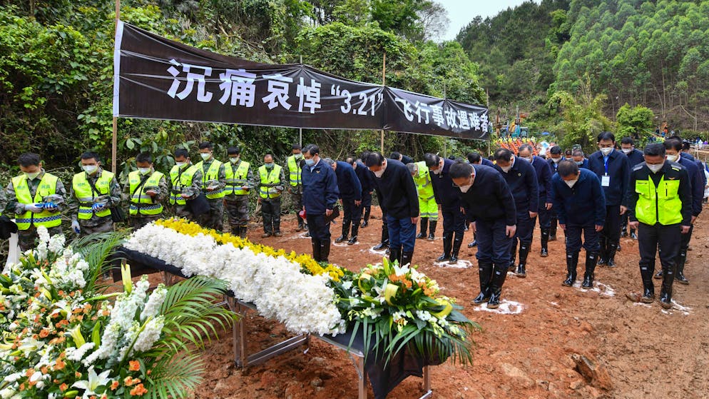 In this photo released by Xinhua News Agency, officials and search and rescue workers bow and pause for a three-minute moment of silence for the 132 people killed, at the China Eastern flight crash site in Tengxian County on Sunday, March 27, 2022, in southern China's Guangxi Zhuang Autonomous Region. The second