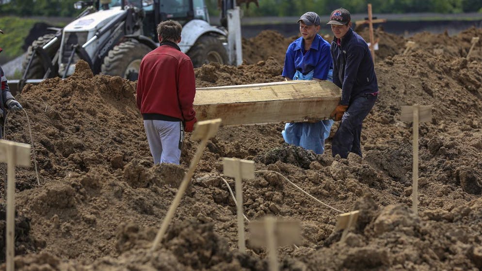 Der Krieg in der Ukraine in Bildern. <strong>22. Mai: </strong>Mitarbeiter des örtlichen Friedhofs in Staryj Krym bei Mariupol tragen einen Sarg zu einem frisch ausgehobenen Grab. 