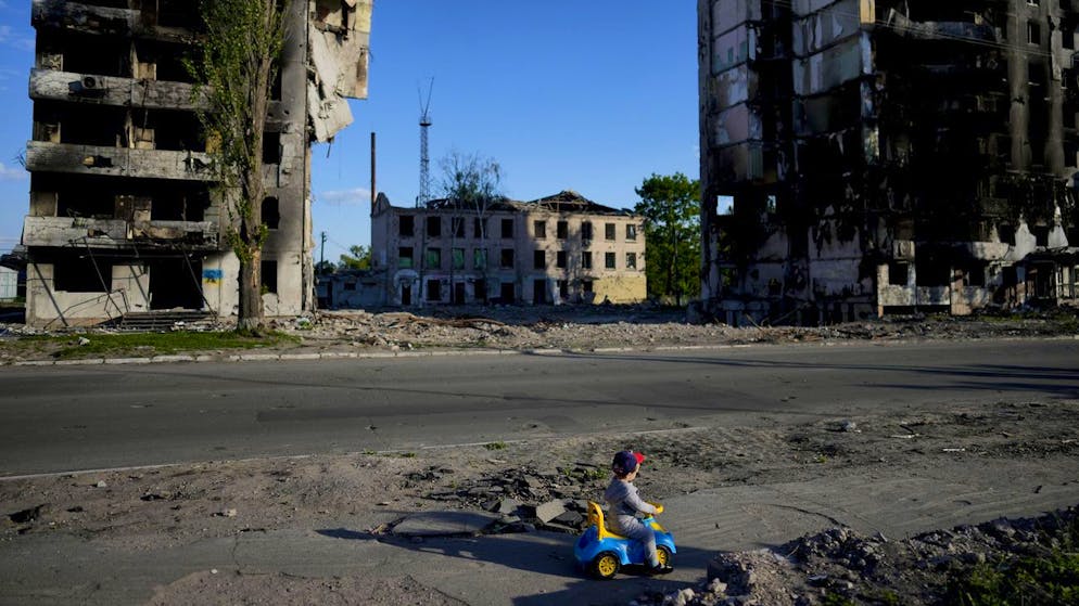 Der Krieg in der Ukraine in Bildern. <strong>24. Mai:</strong> Ein kleiner Junge spielt auf der Strasse in Borodyanka vor zerstörten Wohnblocks.