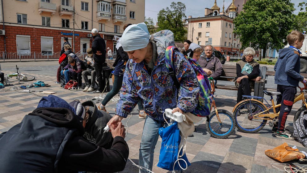 epa09964973 Local people charge their cellphones outside the destroyed Drama Theatre in Mariupol, Ukraine, 21 May 2022 (issued 22 May 2022). The Chief spokesman of the Russian Defense Ministry, Major General Igor Konashenkov, said on 20 May that the long-besieged Azovstal steel plant in Mariupol was under full Russian army control. EPA/ALESSANDRO GUERRA