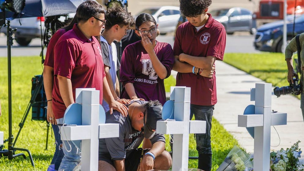 epa09978790 People leave flowers and sign messages on crosses bearing the names of victims in the city park following a mass shooting at the Robb Elementary School in Uvalde, Texas, USA, 26 May 2022. According to Texas officials, at least 19 children and two adults were killed in the shooting on 24 May. The eighteen-year-old gunman was killed by responding officers. EPA/TANNEN MAURY