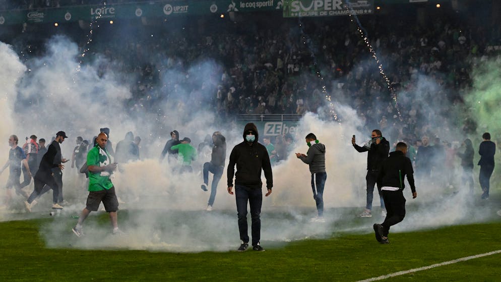 TOPSHOT - Saint-Etienne's fans invade the pitch through smoke after being defeated at the end of the French L1-L2 play-off second leg football match between AS Saint-Etienne and AJ Auxerre at the Geoffroy Guichard Stadium in Saint-Etienne, central-eastern France on May 29, 2022. (Photo by JEAN-PHILIPPE KSIAZEK / AFP) (Photo by JEAN-PHILIPPE KSIAZEK/AFP via Getty Images)