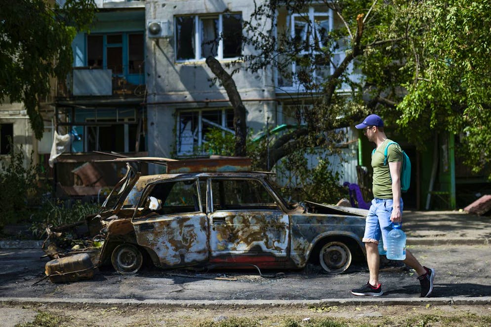 A man carries water in front of an apartment building damaged in an overnight missile strike, in Sloviansk, Ukraine, Tuesday, May 31, 2022. In towns and cities near the fighting in eastern Ukraine, artillery and missile strikes have downed power lines and punched through water pipes, leaving many without electricity or water as repair crews race to repair the damage. (AP Photo/Francisco Seco)