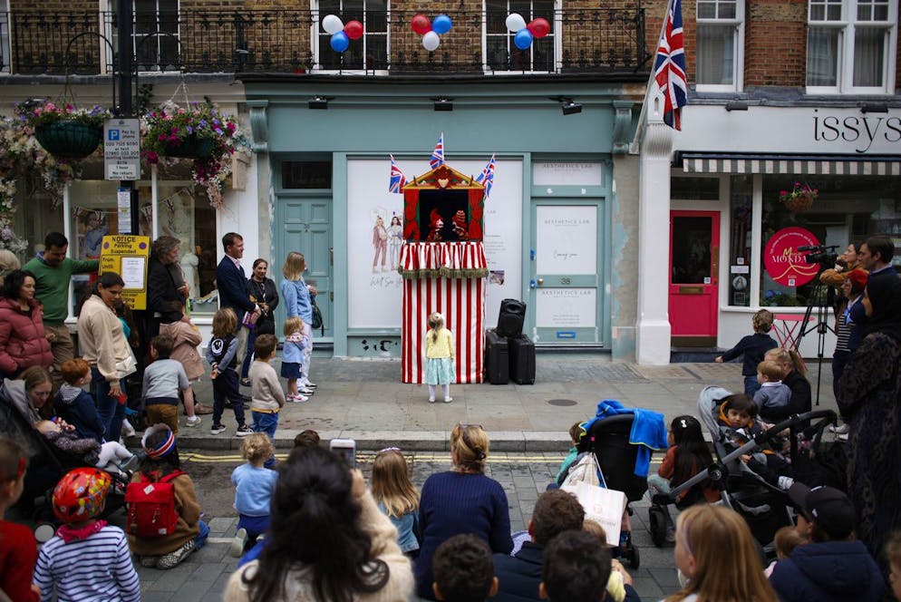 A young girl looks up at a Punch and Judy show during a public street party in Elizabeth Street in central London, Sunday June 5, 2022, on the last of four days of celebrations to mark the Platinum Jubilee. Street parties are set to be held across the country in what is being called The Big Jubilee Lunch. The events over a long holiday weekend in the U.K. have celebrated Queen Elizabeth II's 70 years of service. (AP Photo/David Cliff)