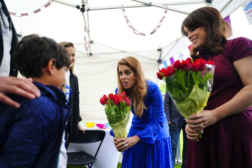 Britain's Princess Beatrice, center, and Princess Eugenie are presented with flowers as they arrive at the Big Jubilee Lunch organised by Westminster Council for local volunteer and community groups who helped during the Covid-19 pandemic, at Paddington Recreation Ground, on the last of four days of celebrations to mark Queen Elizabeth II's Platinum Jubilee, in London, Sunday, June 5, 2022. (Victoria Jones/PA via AP)