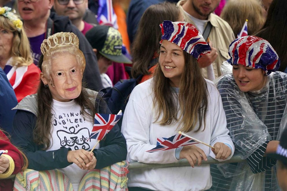 People, including a girl wearing a cut out face mask of Queen Elizabeth II, gather for the Platinum Jubilee Pageant in front of Buckingham Palace, in London, Sunday June 5, 2022, on the last of four days of celebrations to mark the Platinum Jubilee. The pageant will be a carnival procession up The Mall featuring giant puppets and celebrities that will depict key moments from the Queen Elizabeth IIâÄ™s seven decades on the throne. (Yui Mok/PA via AP)