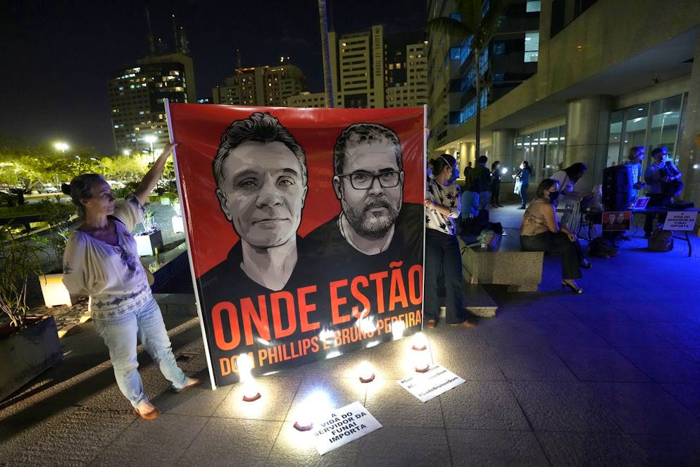 Employees of the National Indigenous Foundation, FUNAI, display a large poster with images of British journalist Dom Phillips, left, and Indigenous affairs expert Bruno Araujo Pereira, and with the Portuguese phrase