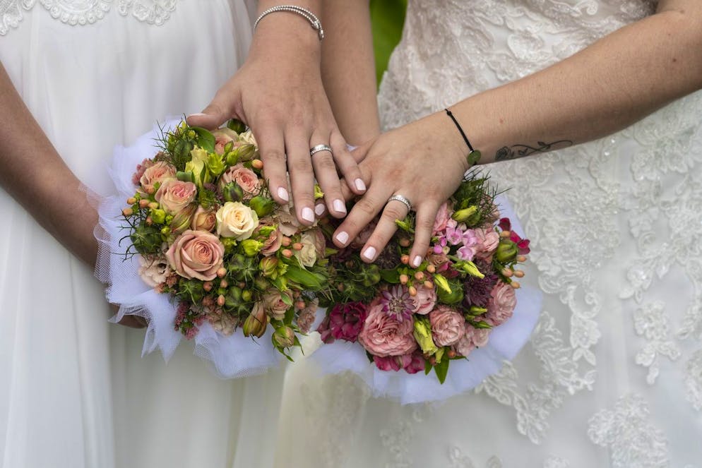 Die Haende von Laura und Delia mit ihren Eheringen liegen fuer ein Foto auf den Blumenstraeussen, fotografiert am 7. August 2021 in Regensberg, Kanton Zuerich. (KEYSTONE/Gaetan Bally)