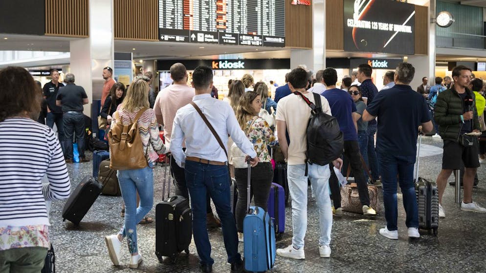 Fluggaeste warten vor einer Anzeigetafel am Mittwoch, 15. Juni 2022, auf dem Flughafen in Zuerich. Wegen einer Informatikpanne von Skyguide sind die Flughaefen Zuerich und Genf derzeit lahmgelegt. Es koennen weder Flugzeuge starten noch landen, wie eine Sprecherin in Zuerich auf Anfrage sagte. Auch Ueberfluege ueber die Schweiz sind nicht moeglich. (KEYSTONE/Ennio Leanza).