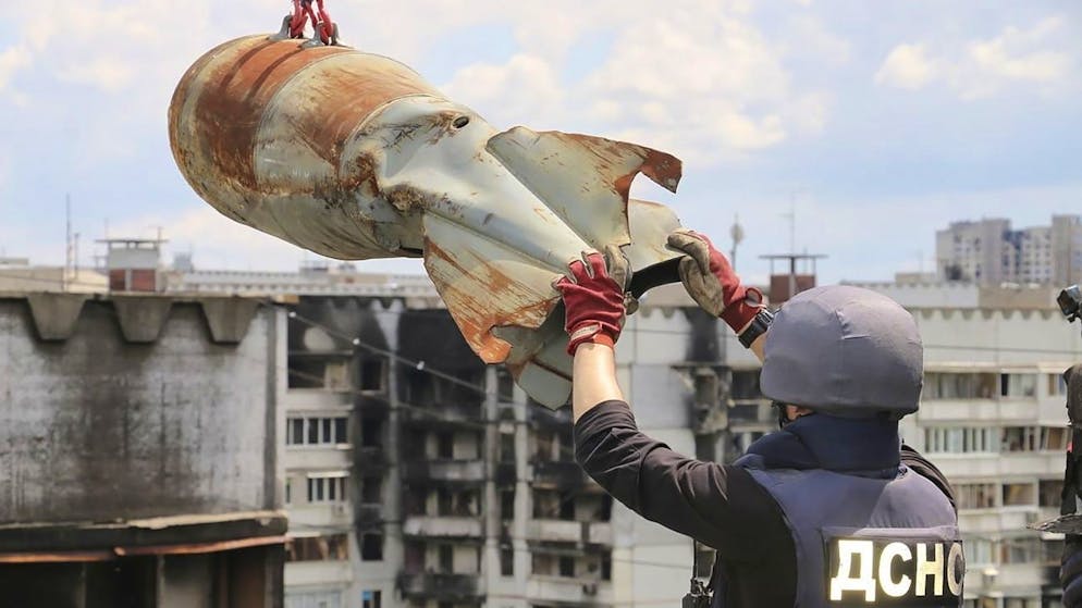 Ein Mitarbeiter des ukrainischen Katastrophenschutzes hilft beim Entfernen einer nicht explodierten Fliegerbombe aus einem Wohngebäude in Charkiw am 23. Juni 2022. 