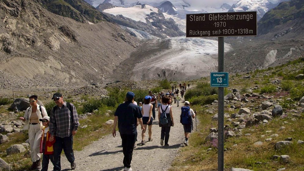 Wanderer pilgern am Dienstag, 22. Juli 2003 in grossen Scharen zum Morteratschgletscher bei Pontresina im Oberengadin. Auf der Suche nach Abkuehlung spazieren tagtaeglich unzaehlige Wanderer von der Station Morteratsch zum Fusse des Morteratschgletschers im Berninagebiet. Dabei wird der Fussmarsch Jahr fuer Jahr um einige Minuten laenger. Wie bei praktisch allen Schweizer Gletschern schwinden auch die Eismassen des Morteratschgletschers in horrendem Tempo, in diesem Sommer noch schneller als sonst. (KEYSTONE/Arno Balzarini)