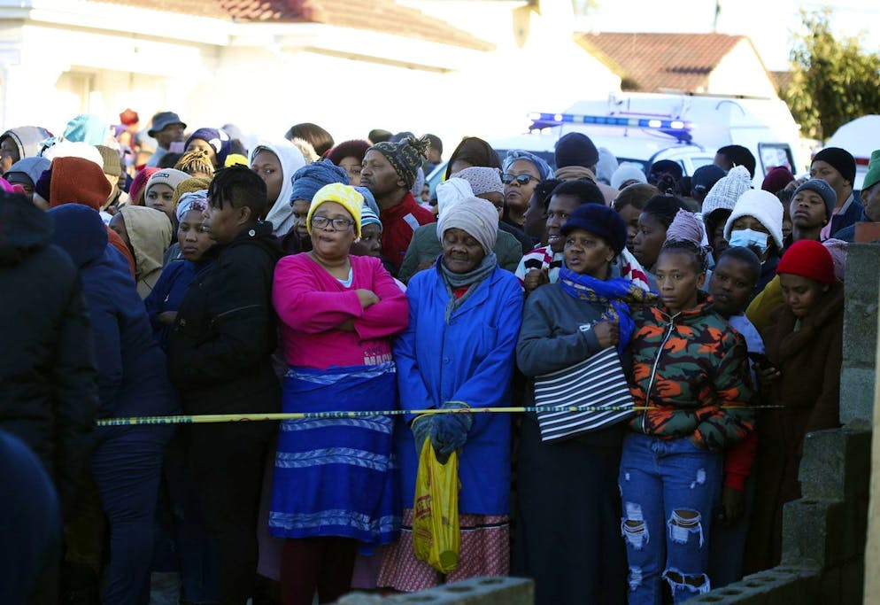 People stand behind a police cordon outside a nightclub in East London, South Africa, Sunday June 26, 2022. South African police are investigating the deaths of at least 20 people at a nightclub in the coastal town of East London early Sunday morning. It is unclear what led to the deaths of the young people, who were reportedly attending a party to celebrate the end of winter school exams. (AP Photo)