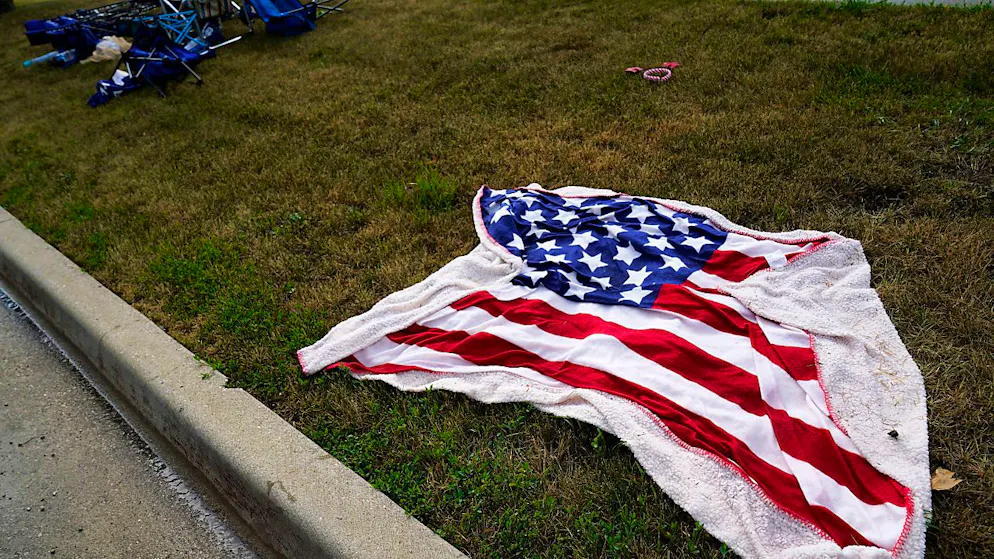 Leere Stühle und eine Decke mit amerikanischer Flagge liegen auf dem Boden, nachdem ein Schütze bei einer Parade anlässlich des Nationalfeiertags in den USA das Feuer eröffnet hatte. Foto: Nam Y. Huh/AP/dpa