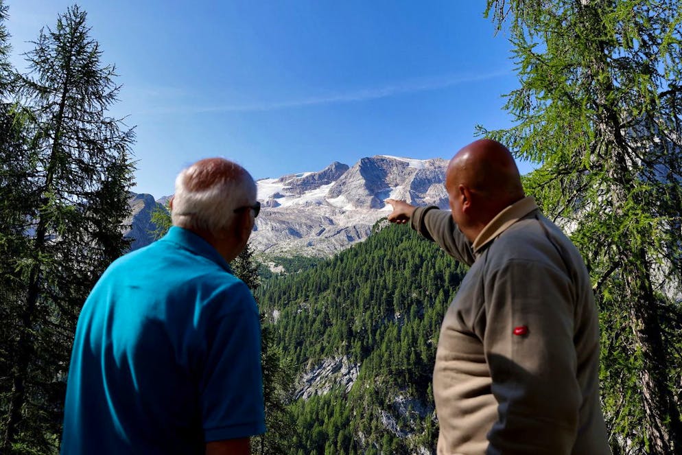 epa10051092 People look at the Marmolada Mountain in the aftermath of an avalanche in Canazei, Italy, 04 July 2022. At least six people were killed and dozens were still missing on 04 July, a day after a glacier collapsed triggering an avalanche on the multi-peak mountain of the Italian Dolomites. EPA/ANDREA SOLERO