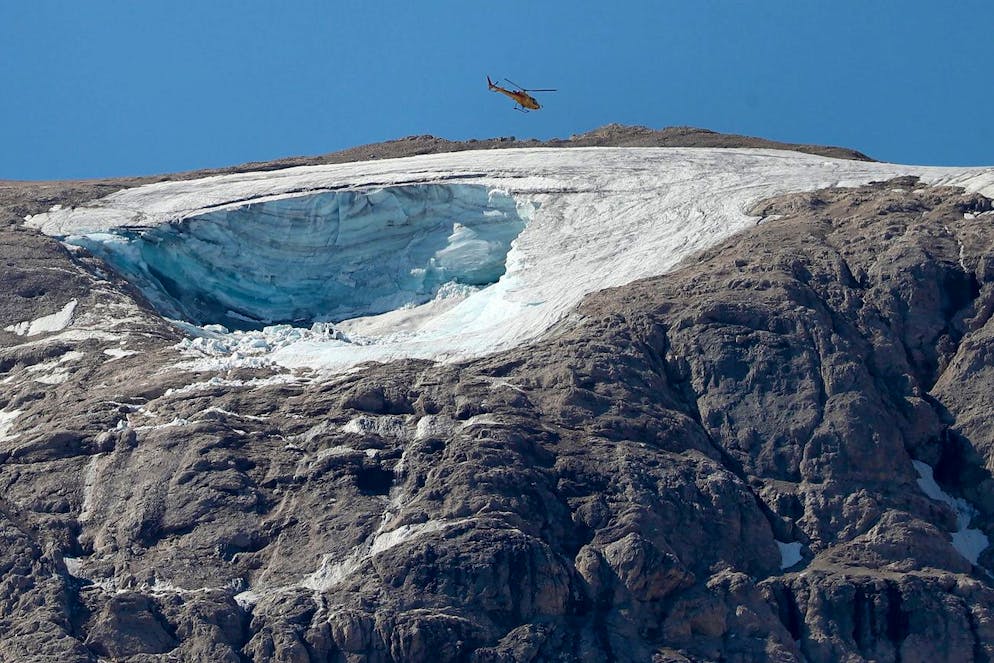 epa10051091 A helicopter flies over the missing part of a glacier that collapsed triggering an avalanche on the Marmolada Mountain, in Canazei, Italy, 04 July 2022. At least six people were killed and dozens were still missing on 04 July, a day after the avalanche hit the multi-peak mountain. EPA/ANDREA SOLERO