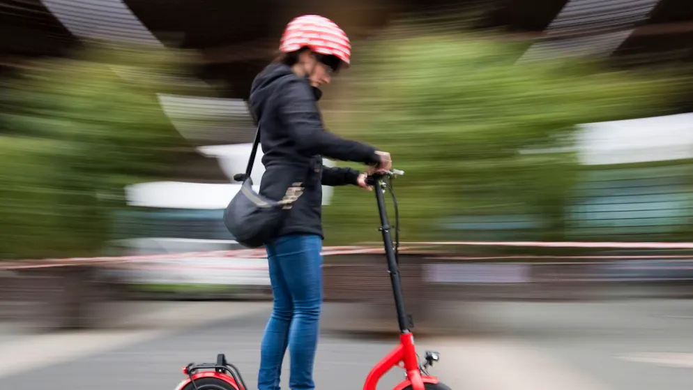 Velohelm aufsetzen: Eine Frau auf einem E-Trottinett handelt nach den Empfehlungen der Polizei. (Archivbild)