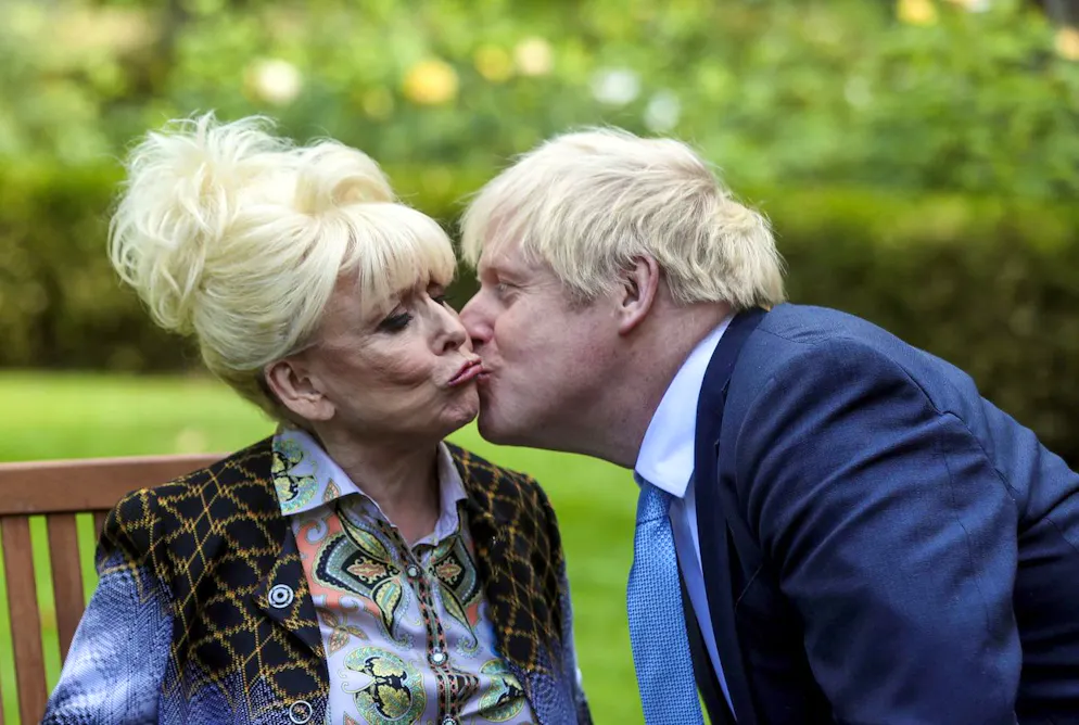 Best of Boris Johnson. Auf den Mund oder doch lieber auf die Wange? Ach, egal. Die Frau, die im Jahr 2020 von Boris Johnson geküsst wird, ist übrigens Schauspielerin Barbara Windsor. 