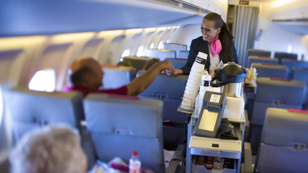 Eine Flugbegleiterin verteilt Essen und Getränke an die Passagiere. (Archivbild)