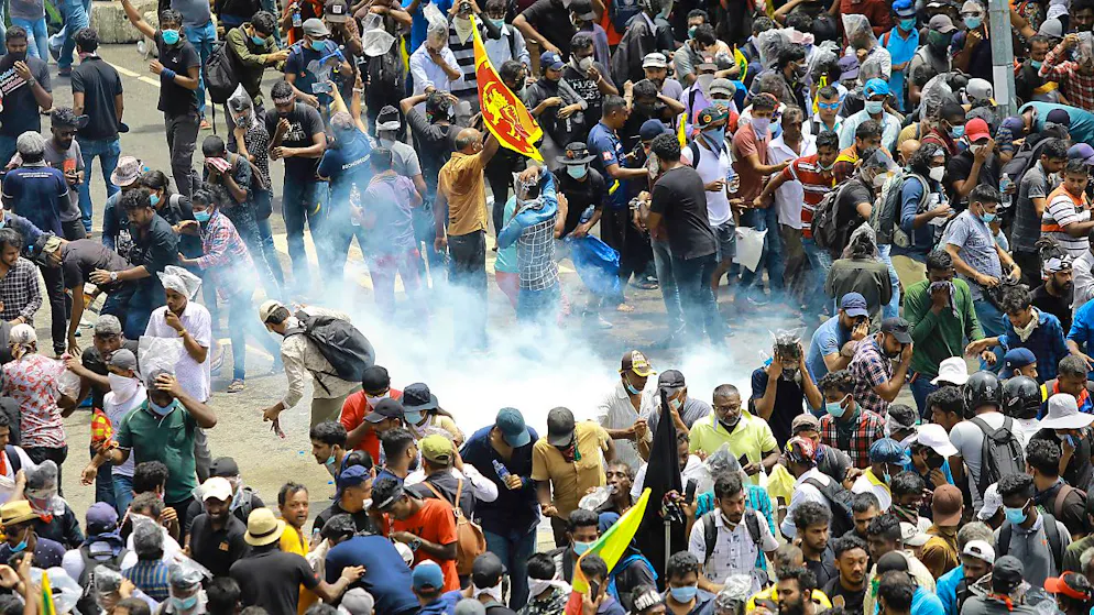 Demonstranten reagieren, als eine von der Polizei abgefeuerte Tränengasgranate neben ihnen landet. Foto: Amitha Thennakoon/AP/dpa