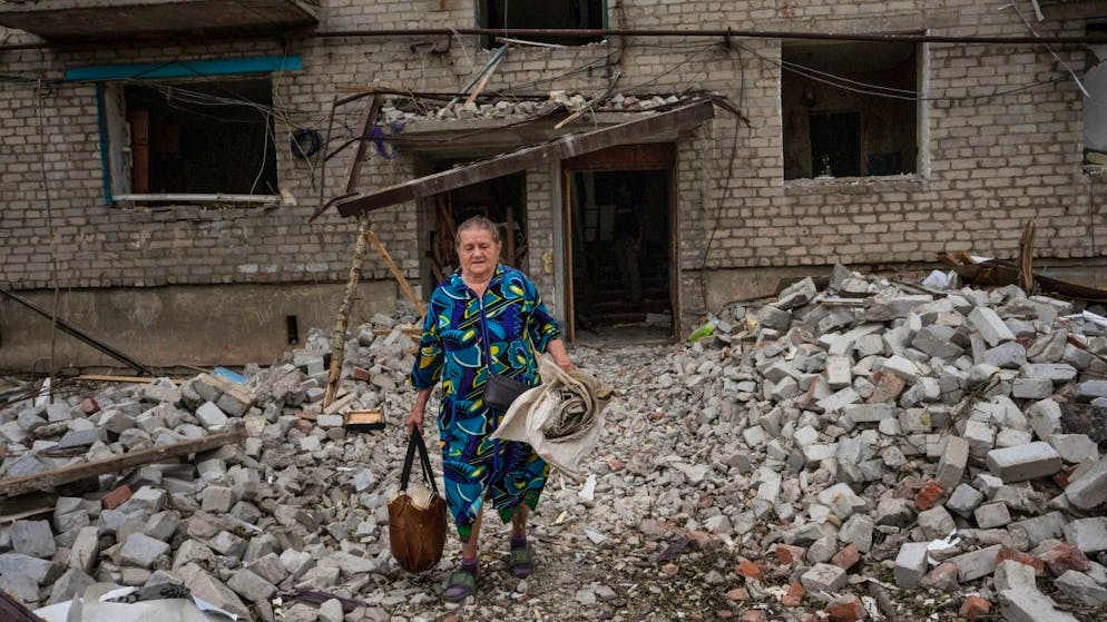 Eine Frau verlässt ihr Haus in Tschassiw Jar mit Habseligkeiten, nachdem eine Rakete den Wohnblock getroffen hat. Mehrere Menschen wurden bei dem Anschlag verletzt und getötet. Foto: Nariman El-Mofty/AP/dpa