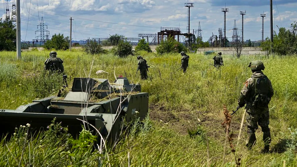 Russische Soldaten untersuchen eine Wiese in der Ukraine auf Minen. (Archiv)