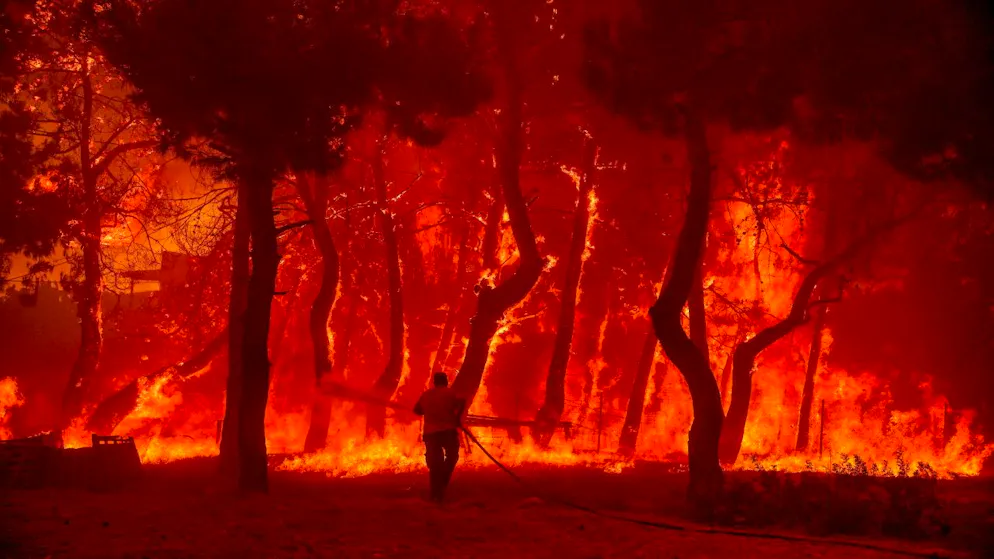 dpatopbilder - Ein Mann geht mit einem Löschschlauch auf die Flammen eines Waldbrandes auf der Ferieninsel Lesbos zu. Foto: Eurokinissi/Eurokinissi via ZUMA Press Wire/dpa