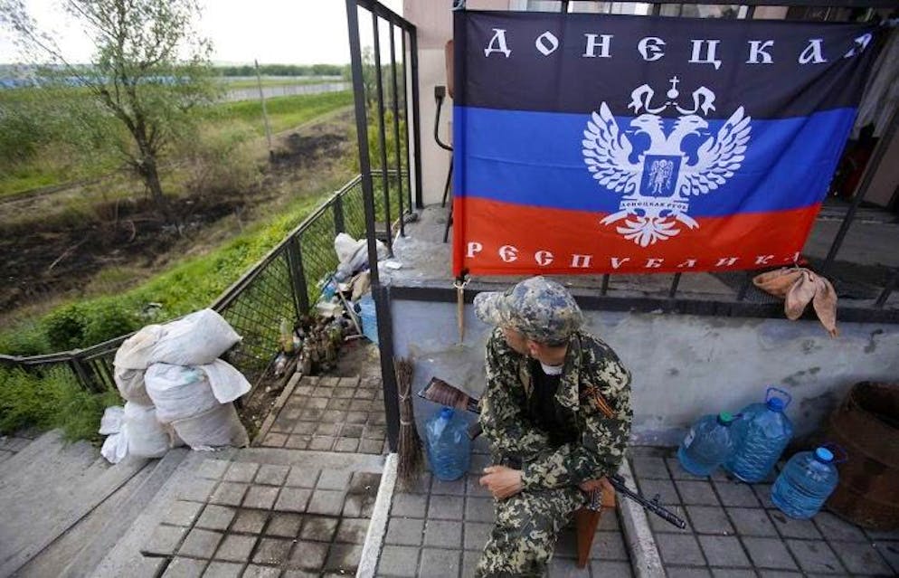 Un separatista filorusso siede davanti alla bandiera dell'autoproclamata Repubblica di Donetsk.