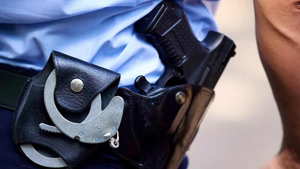 ARCHIV - Ein Polizist trägt Handschellen und seine Dienstwaffe bei sich. Foto: Oliver Berg/dpa/Symbolbild