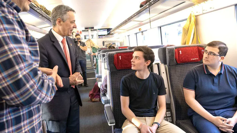 Bundespräsident Ignazio Cassis spricht auf seiner «Reise durch die moderne Schweiz»mit zwei Fahrgästen.