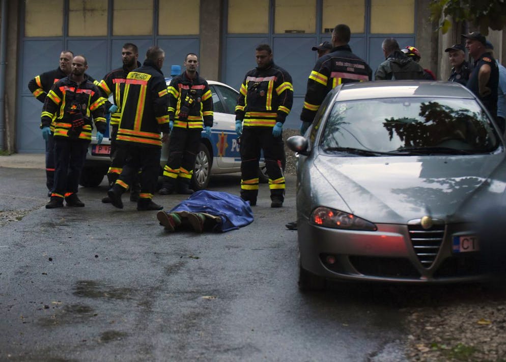 Des pompiers se tenant près d'un corps sur le site de l'attaque à Cetinje, à quelque 30 km à l'ouest de Podgorica, au Monténégro.