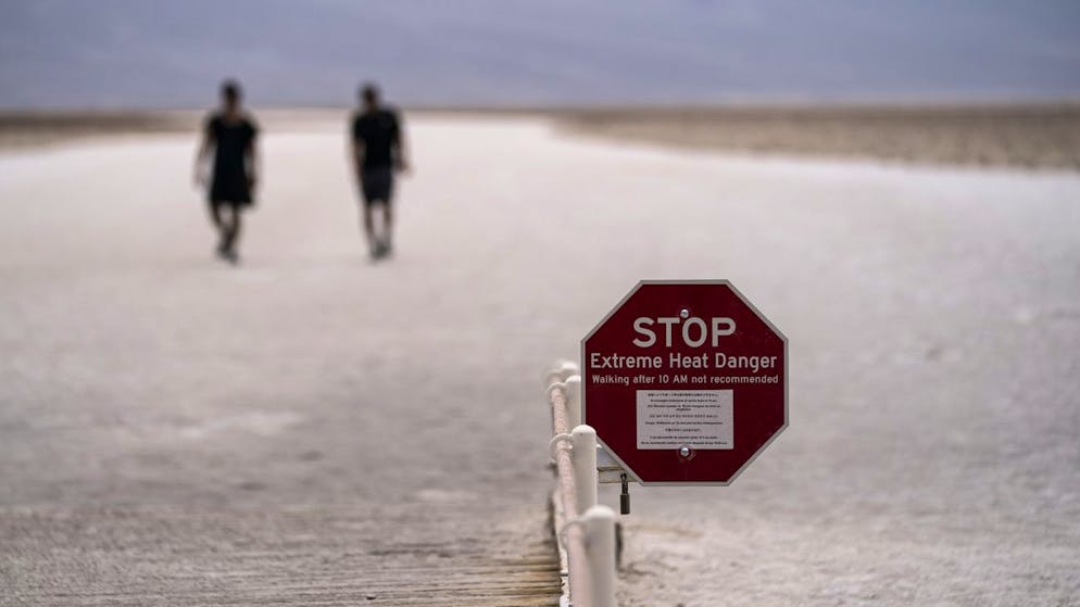 A Sign Warns Of The Danger Of Extreme Heat As People Walk On Salt Flats In Badwater Basin, Sunday, July 11, 2021, In Death Valley National Park, Calif.  Death Valley In Southeastern California'S Mojave Desert Reached 128 Degrees Fahrenheit (53 Celsius) On Saturday.  According To Readings From The National Weather Service In Furnace Creek.  The Shockingly High Temperature Was Actually Lower Than The Previous Day, When The Location Reached 130 F (54 C).  (Ap Photo/John Locher)