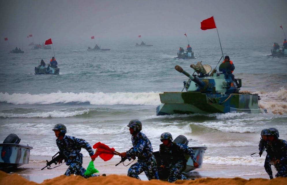 Amphibious tanks and Marine Corps soldiers rush to the beachhead in an amphibious landing drill during the third phase of the Sino-Russian 