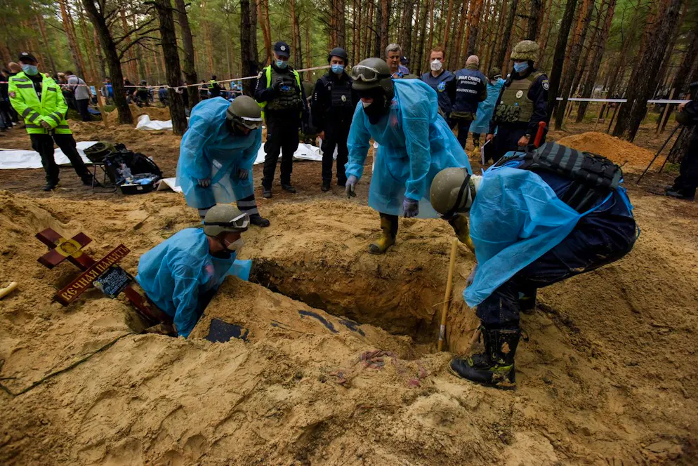 Des agents des services d'urgence ukrainiens exhument des corps de tombes près d'Izioum, région de Kharkiv, nord-est de l'Ukraine, 16 septembre 2022.