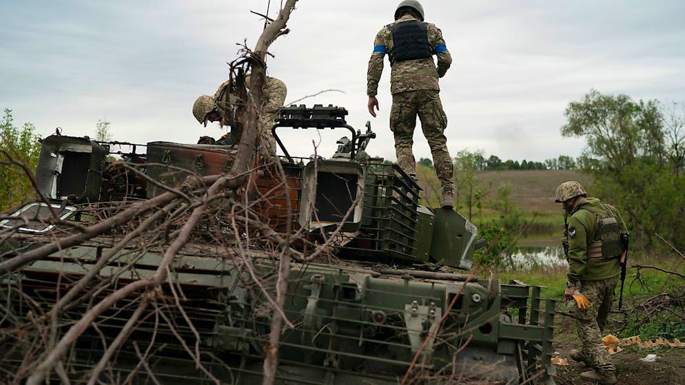Ukrainische Soldaten begutachten einen zerstörten russischen Panzer in einem zurückeroberten Gebiet nahe Charkiw.