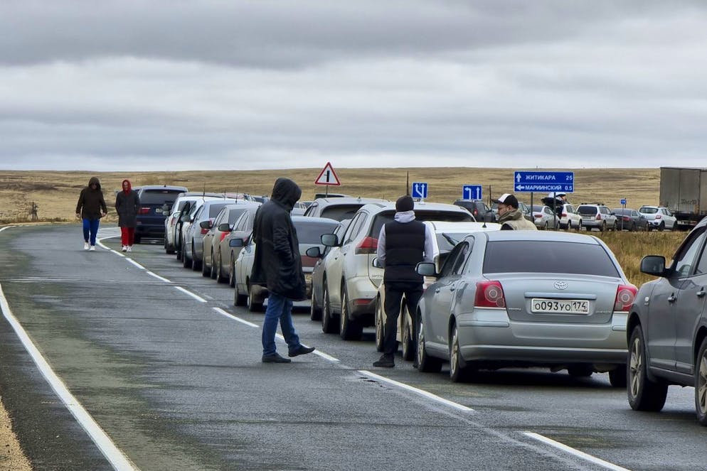 Les gens marchent à côté de leurs voitures faisant la queue pour traverser la frontière avec le Kazakhstan au poste frontière de Mariinsky, à environ 400 kilomètres au sud de Tcheliabinsk, en Russie, le mardi 27 septembre 2022.