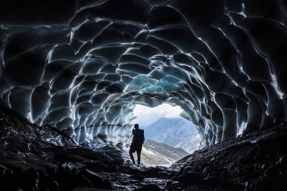 Un uomo in piedi in una grotta nel ghiacciaio di Sardona, a Vaettis mercoledì 27 luglio 2022, creatasi dal ritiro delle nevi perenni a causa dei cambiamenti climatici.