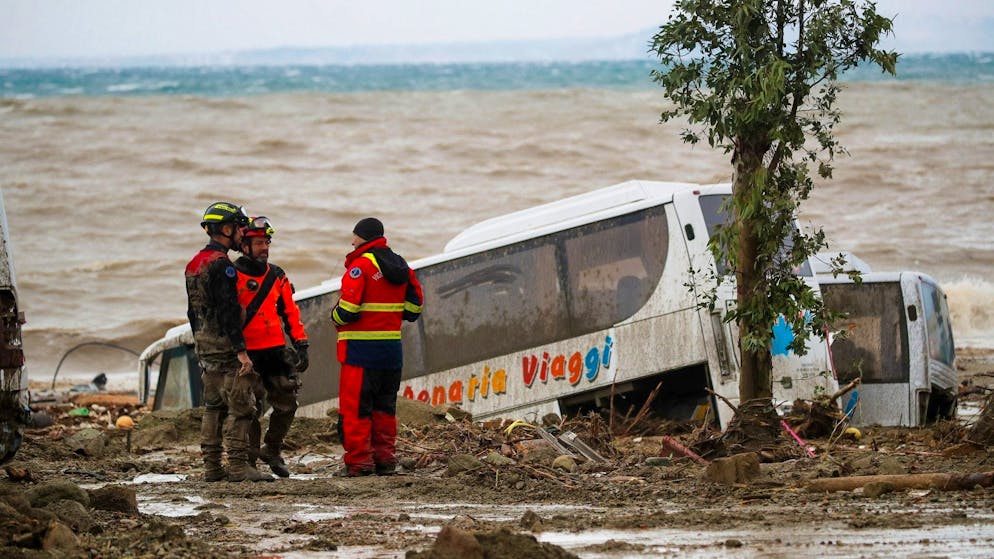 Rettungskräfte auf Ischia neben einem Bus, der durch schwere Regenfälle weggeschwemmt wurde.