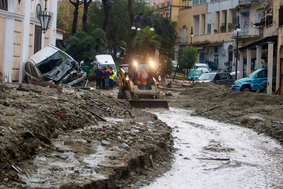 A caterpillar removes mud from a flooded road after heavy rainfall triggered landslides that collapsed buildings and left as many as 12 people missing, in Casamicciola, on the southern Italian island of Ischia, Saturday, Nov. 26, 2022. Firefighters are working on rescue efforts as reinforcements are being sent from nearby Naples, but are encountering difficulties in reaching the island either by motorboat or helicopter due to the weather. (AP Photo/Salvatore Laporta)