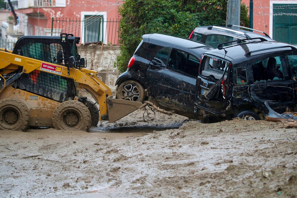 A caterpillar removes damaged cars in a flooded street after heavy rainfall triggered landslides that collapsed buildings and left as many as 12 people missing, in Casamicciola, on the southern Italian island of Ischia, Saturday, Nov. 26, 2022. Firefighters are working on rescue efforts as reinforcements are being sent from nearby Naples, but are encountering difficulties in reaching the island either by motorboat or helicopter due to the weather. (AP Photo/Salvatore Laporta)