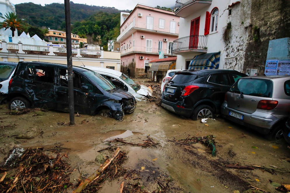 Damaged cars are seen in a flooded road after heavy rainfall triggered landslides that collapsed buildings and left as many as 12 people missing, in Casamicciola, on the southern Italian island of Ischia, Saturday, Nov. 26, 2022. Firefighters are working on rescue efforts as reinforcements are being sent from nearby Naples, but are encountering difficulties in reaching the island either by motorboat or helicopter due to the weather. (AP Photo/Salvatore Laporta)