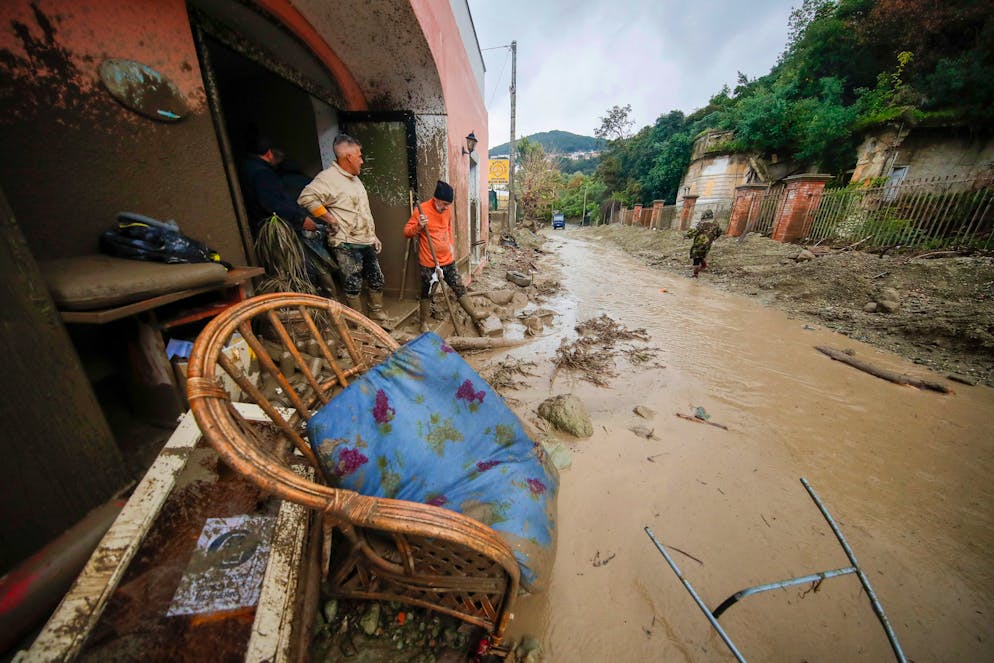 People stand in front of a flooded shop after heavy rainfall triggered landslides that collapsed buildings and left as many as 12 people missing, in Casamicciola, on the southern Italian island of Ischia, Saturday, Nov. 26, 2022. Firefighters are working on rescue efforts as reinforcements are being sent from nearby Naples, but are encountering difficulties in reaching the island either by motorboat or helicopter due to the weather. (AP Photo/Salvatore Laporta)