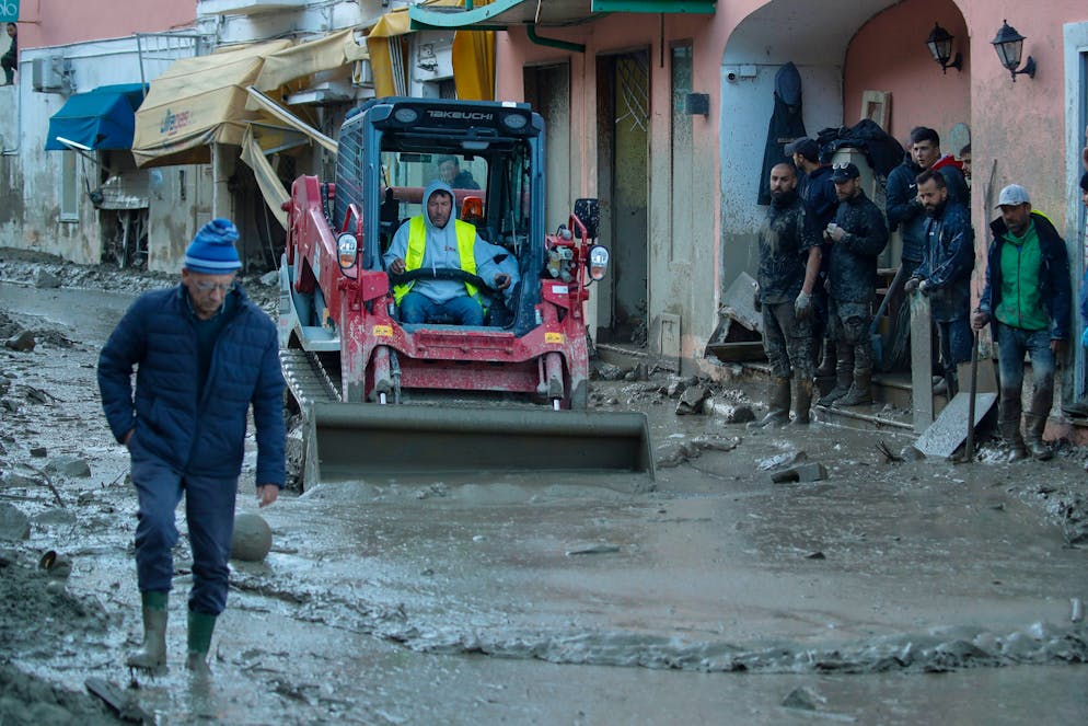Workers clear mud and debris from a street after heavy rainfall triggered landslides that collapsed buildings and left as many as 12 people missing, in Casamicciola, on the southern Italian island of Ischia, Sunday, Nov. 27, 2022. Authorities said that the landslide that early Saturday destroyed buildings and swept parked cars into the sea left one person dead and 12 missing. (AP Photo/Salvatore Laporta)
