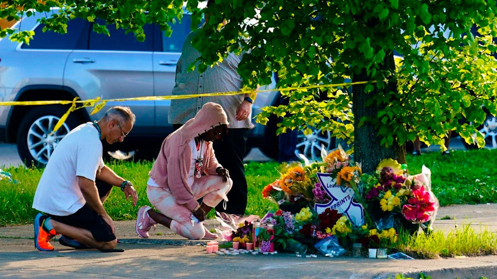 dpatopbilder - ARCHIV - Menschen knien vor Blumen, um den Opfern tödlicher Schüsse in einem Supermarkt in Buffalo die letzte Ehre zu erweisen. Ein Schütze hatte am Samstag (14.05.2022) in der Stadt Buffalo im Bundesstaat New York das Feuer eröffnet und mindestens zehn Menschen getötet. Foto: Matt Rourke/AP/dpa