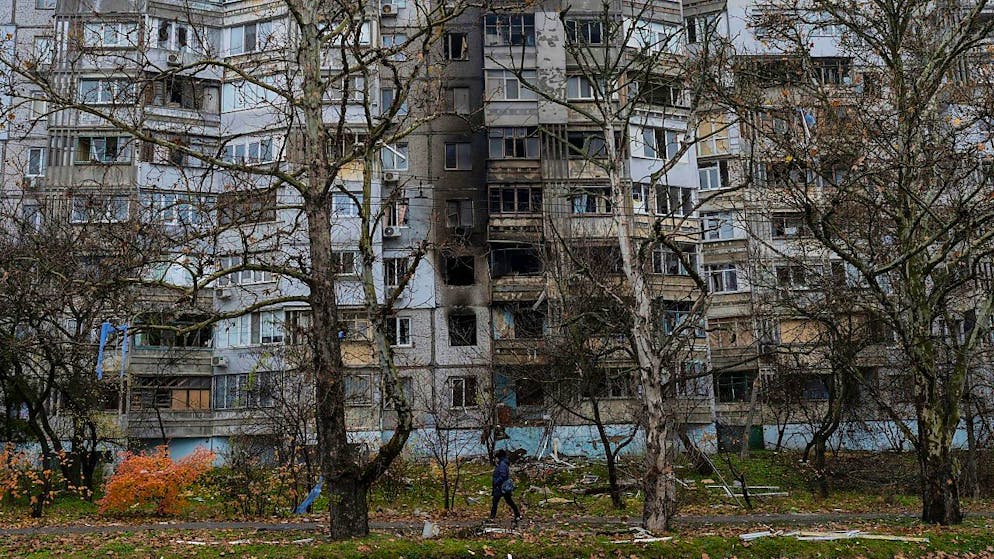Eine Frau geht in Cherson an einem kürzlich durch einen Angriff beschädigten Gebäude vorbei. Foto: Bernat Armangue/AP/dpa