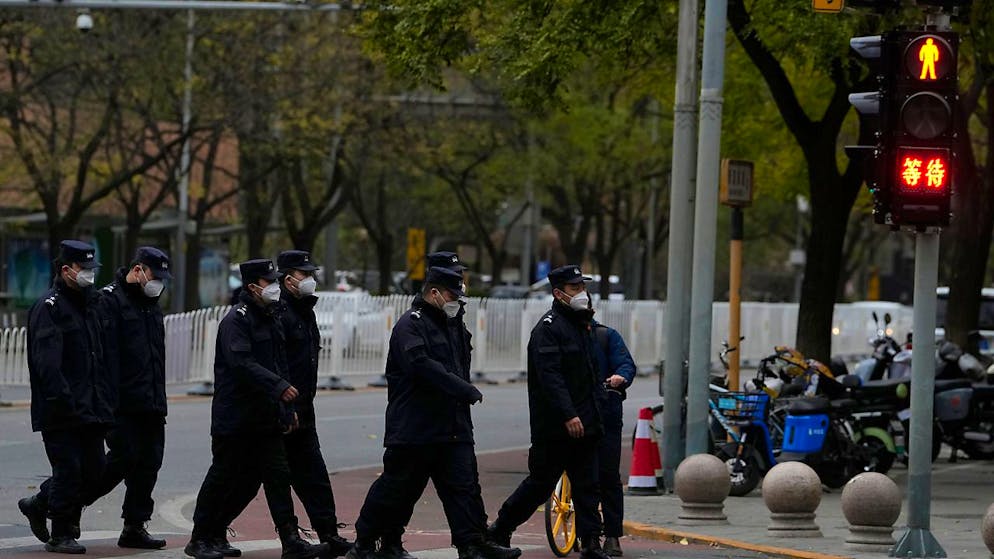 Chinesische Sicherheitskräfte gehen in Peking an einer Kreuzung in der Nähe des Ortes der Proteste vom Vortag vorbei. Foto: Ng Han Guan/AP/dpa