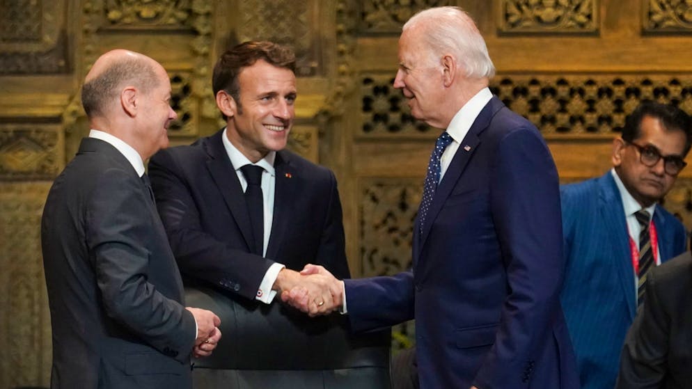 US-Präsident Joe Biden (r) und Frankreichs Präsident Emmanuel Macron begrüssen sich während des G20-Gipfels in Indonesien, daneben steht Bundeskanzler Olaf Scholz (SPD, l).