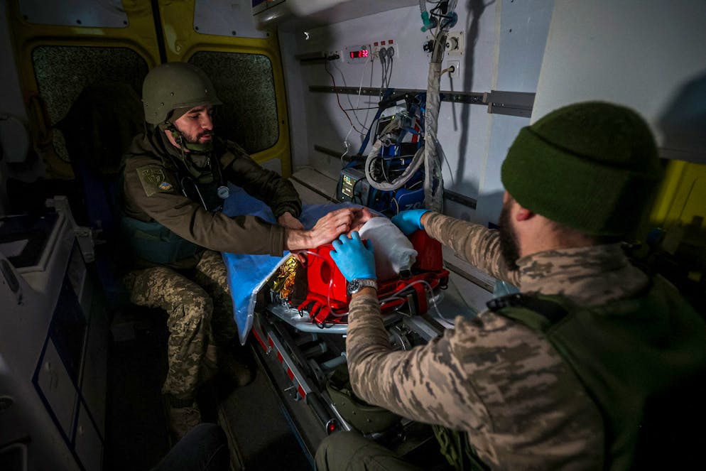 This photograph taken on November 28, 2022, shows volunteer medics from PDMSh (The First Volunteer Mobile Hospital) evacuating a wounded Ukrainian soldier from a stabilizing mobile hospital in the vicinity of Bakhmut, Donetsk region, amid the Russian invasion of Ukraine. - Once known for its vineyards and cavernous salt mines, Bakhmut has now been dubbed 